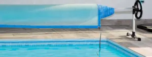 a swimming pool cover on a roller beside a pool